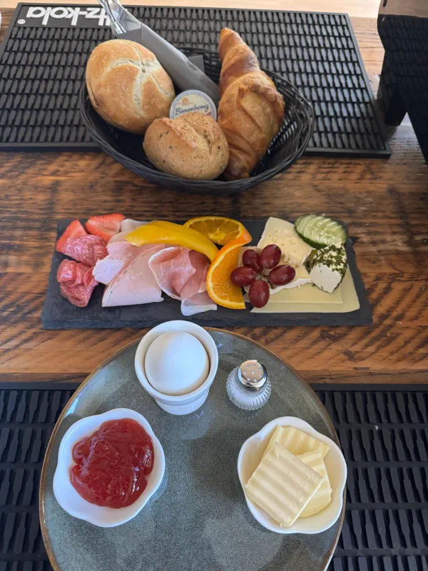 Gemischte Frühstücksplatte mit Aufschnitt, Käse, Obst, Ei, Marmelade, Honig, Butter und Brötchen-Körbchen